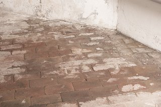 Abgeplatzte Stellen auf Ziegelboden und verschmutzter Wand
